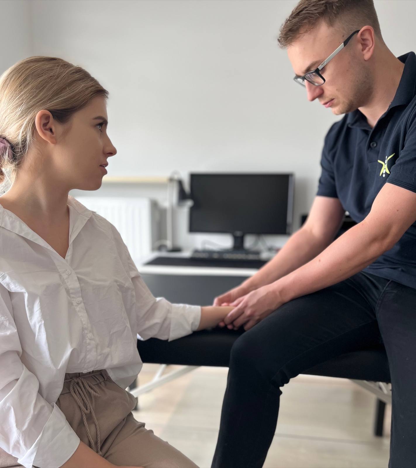 Fizjoterapeuta pracuje z pracownicą bezpośrednio przy stanowisku pracy w biurze